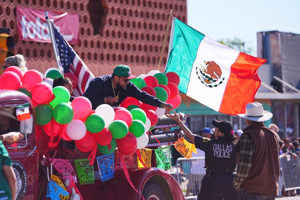 A float rider hands candy to a Dallas police officer during a Cinco de Mayo parade in the Oak...